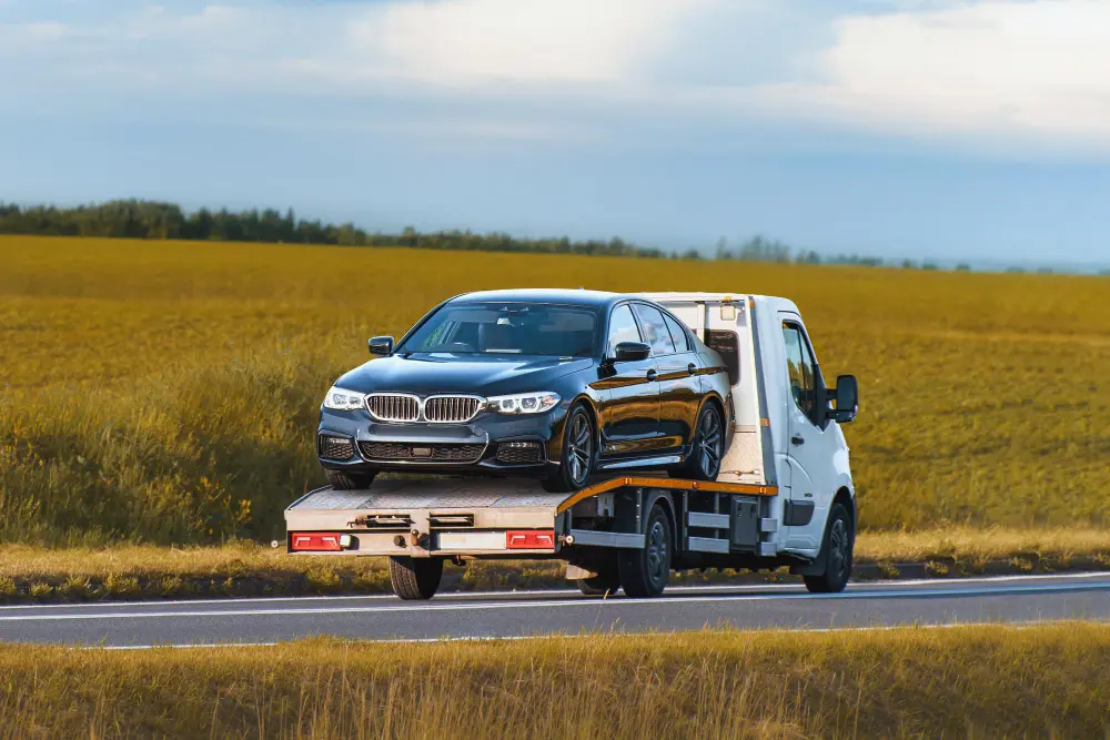 BMW luxury car being transported on a flatbed tow truck