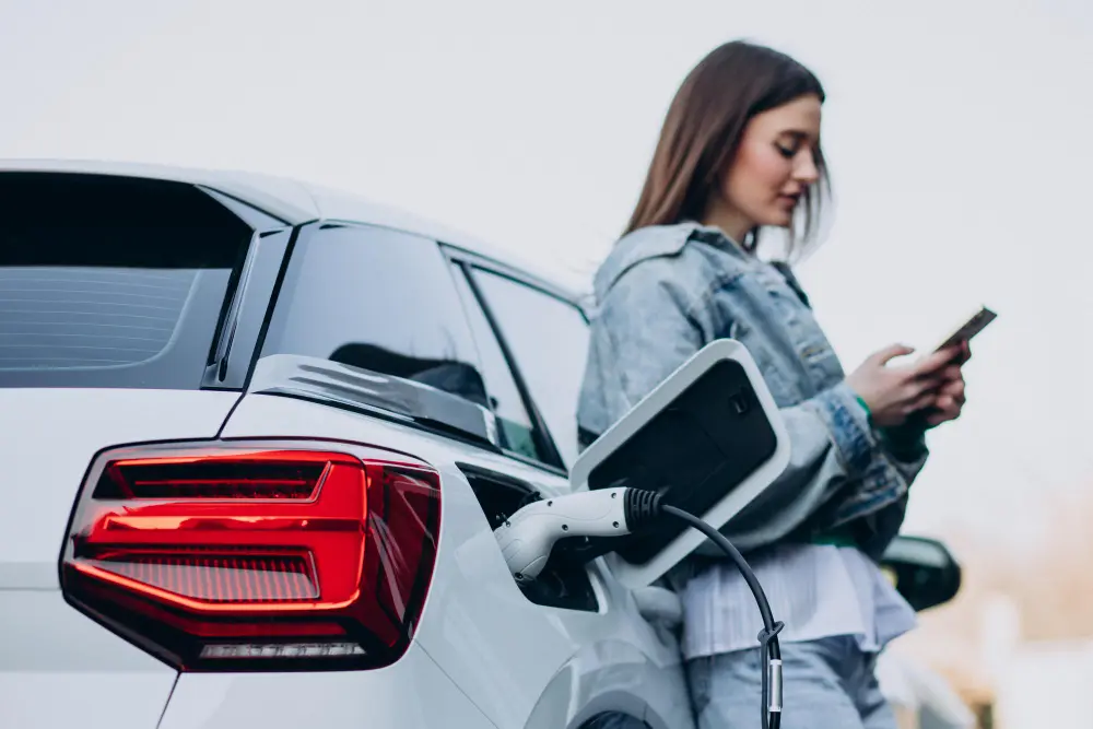 Woman charging an electric vehicle at a charging station