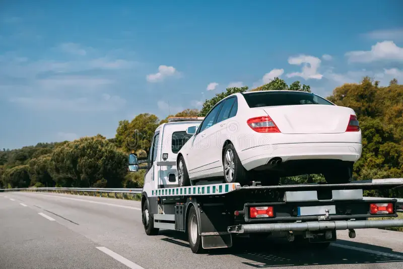 A flatbed tow truck driving on a road in Victoria, representing the legal towing rights and rules that apply to drivers under Victorian law.